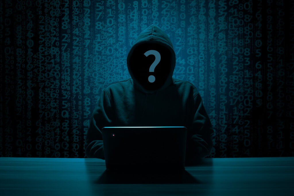 A hacker silhouette behind a computer.